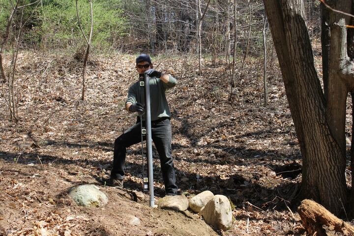Volunteer working on a basket installation beside a wooded fairway