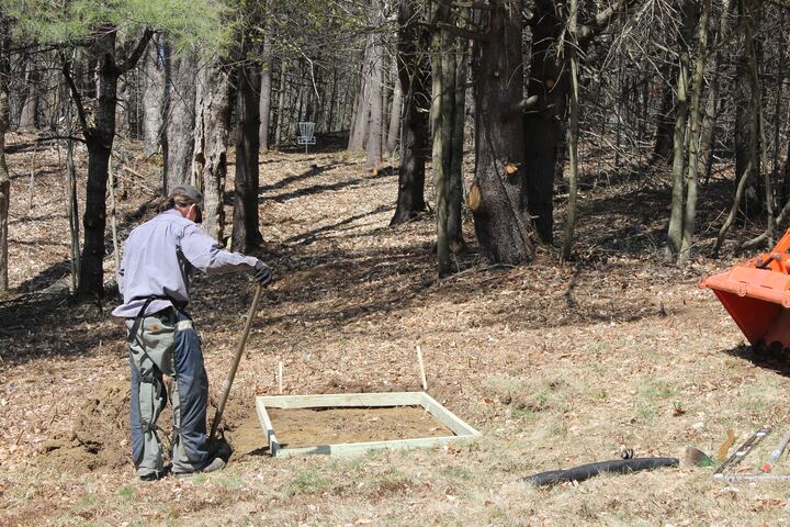 Volunteer preparing a tee pad among the trees